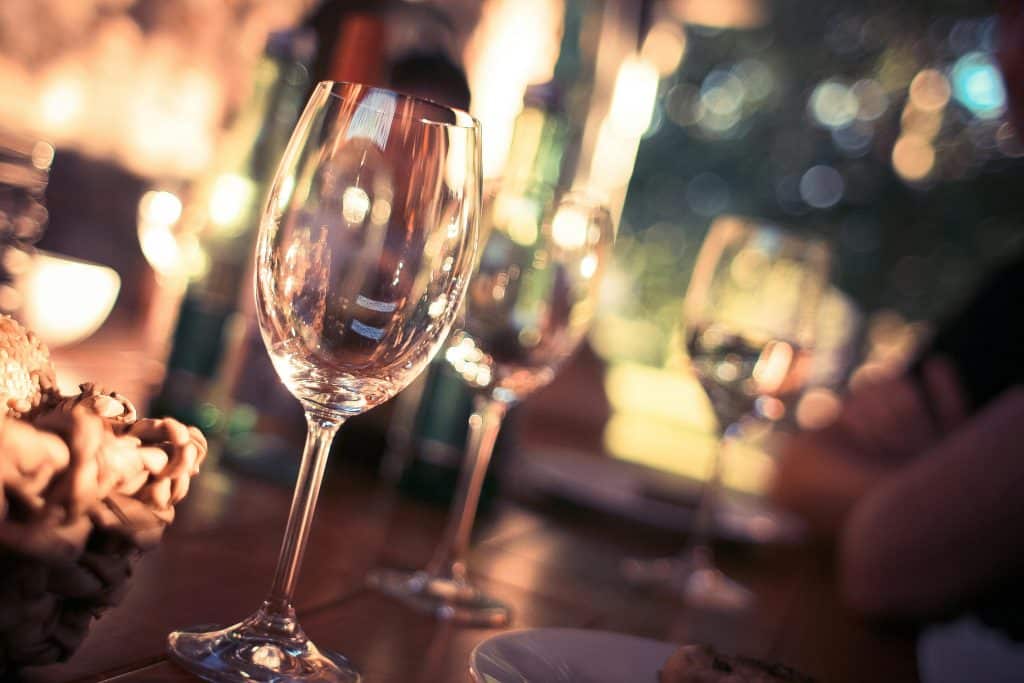 Close-up of wine glasses on a dining table with bokeh lights, creating a warm and inviting atmosphere.