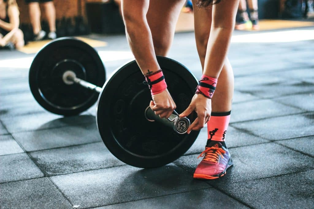 Athlete tightening barbell plates in a gym, emphasizing fitness and strength.